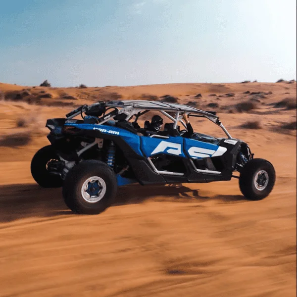 4-seater Can-Am X3 dune buggy on a dune crest at golden hour near Dubai
