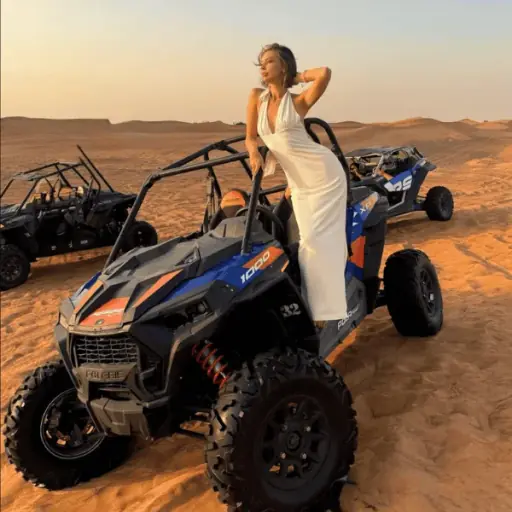 2-seater Polaris RZR dune buggy driving across red dunes in Dubai