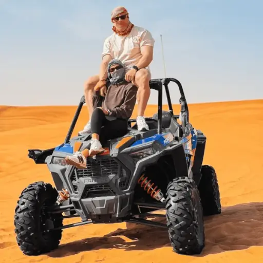 Couple driving a Polaris RZR dune buggy on the Lahbab red dunes near Dubai