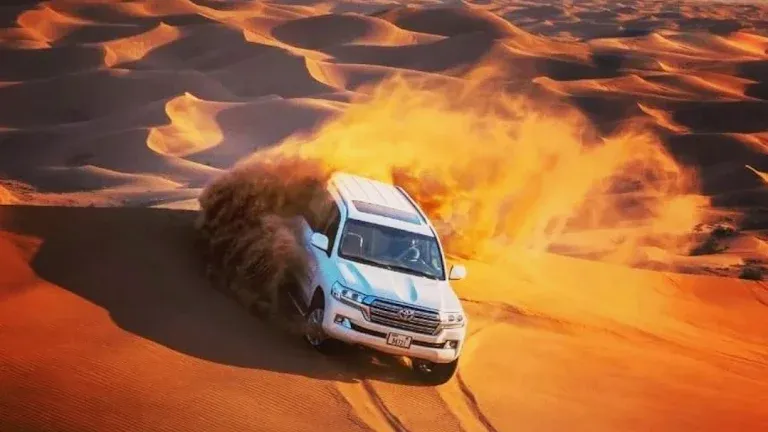 Land Cruiser sliding down a red dune during dune bashing at golden hour