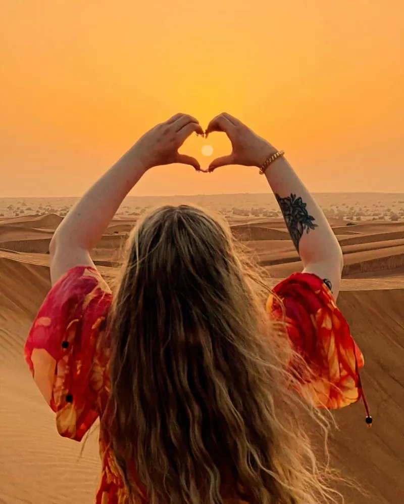Guest framing the setting sun with her hands at the sunset photo stop