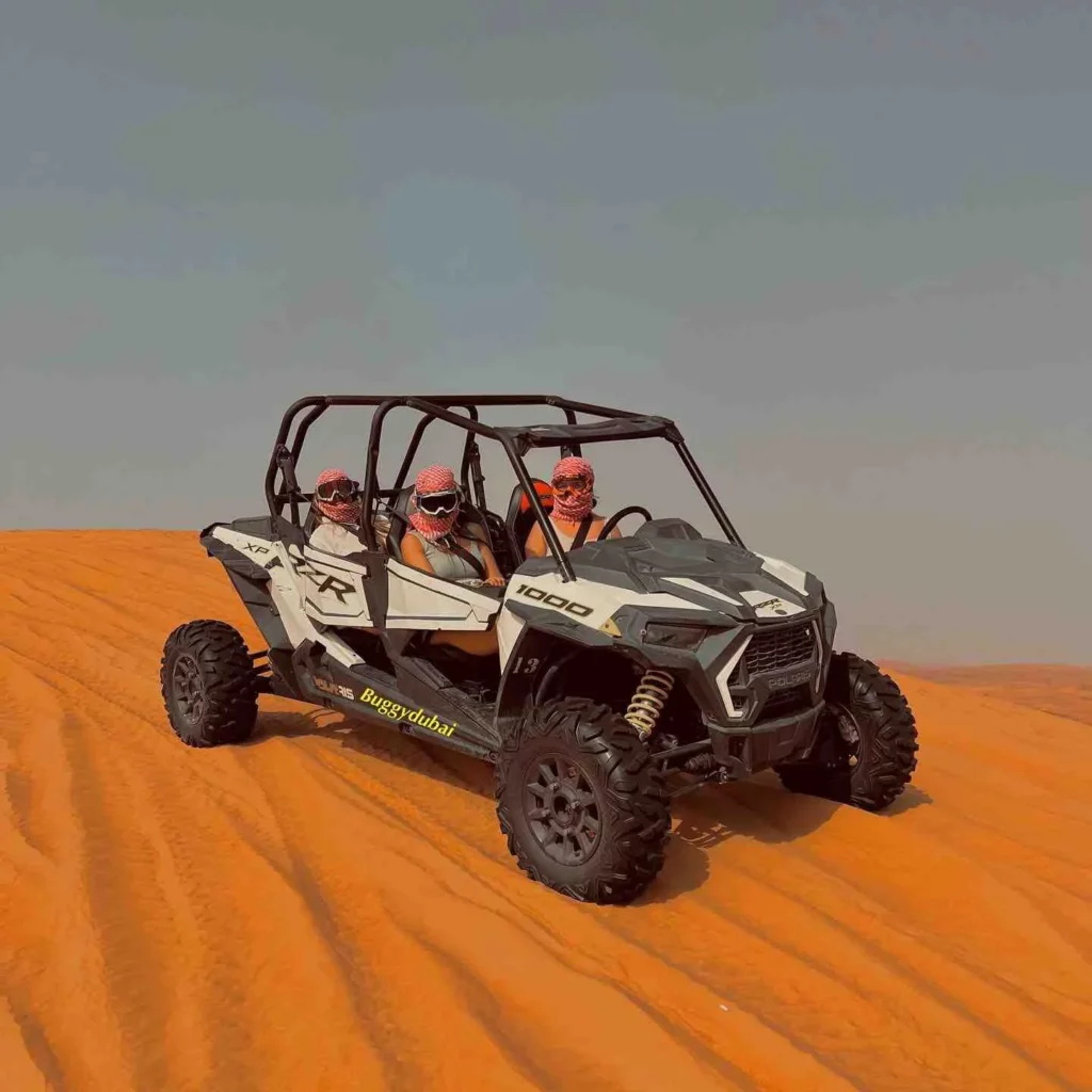 Four people riding a dune buggy in the desert.
