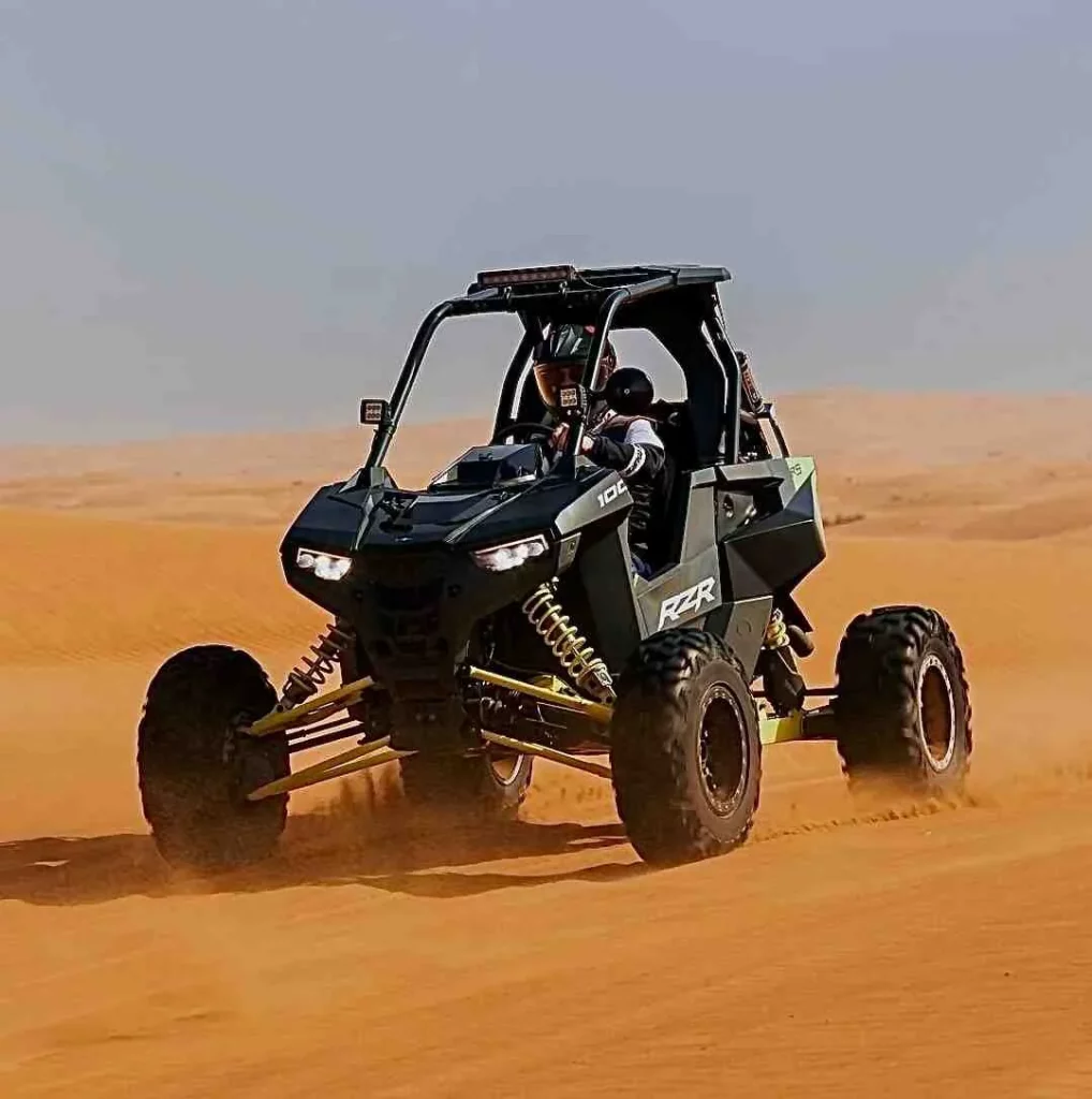 A person riding an off - road dune buggy in the desert.